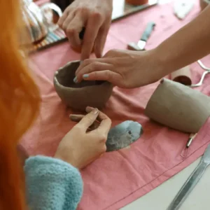 ceramics students watch as a clay bowl is formed by hand