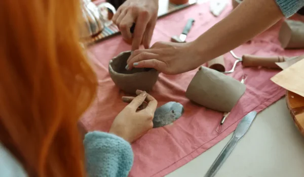 ceramics students watch as a clay bowl is formed by hand