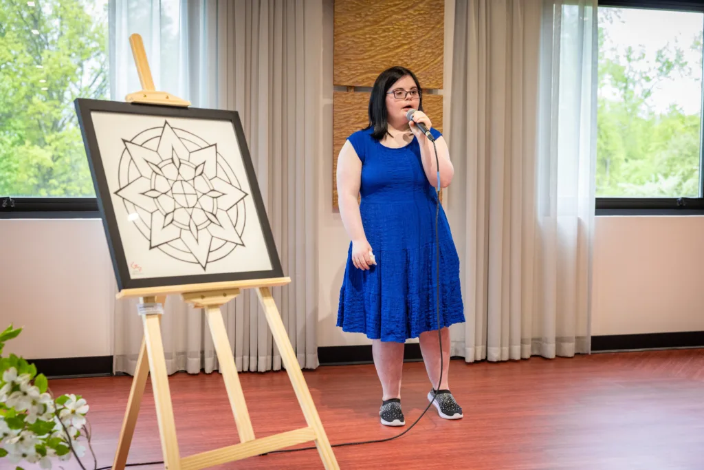 Daniella in a blue dress and sparkly shoes sings a song.