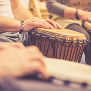 a group of people drum on djembe drums