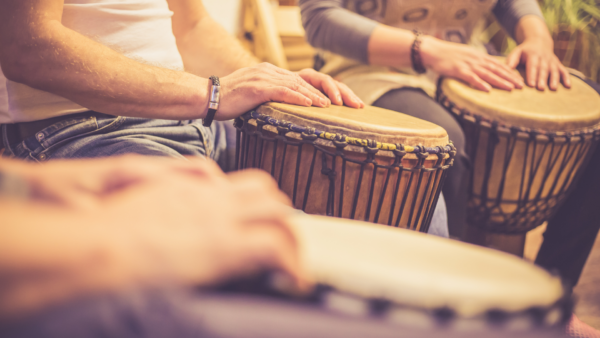 a group of people drum on djembe drums