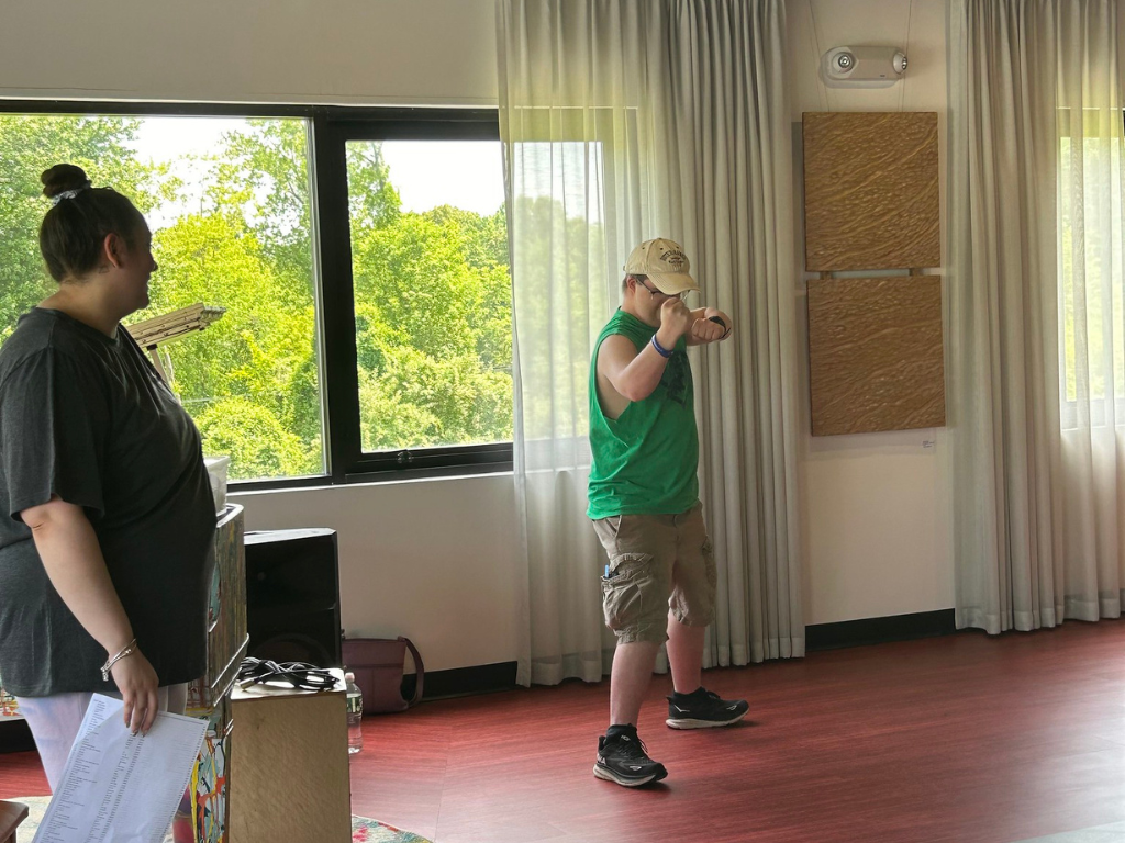 A young man in a green shirt dances while instructor Annie Ayala looks on at Hudson Valley InterArts