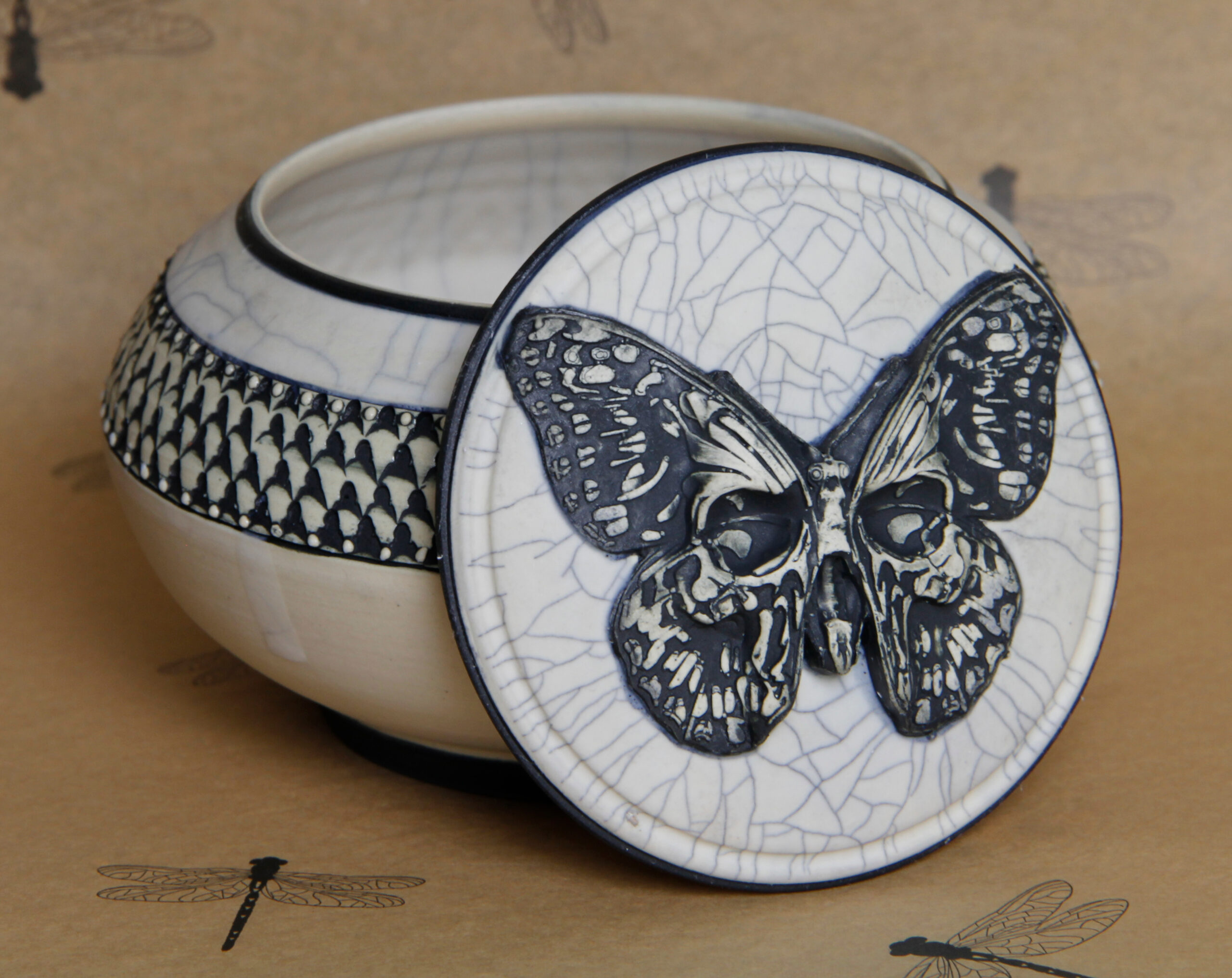 a ceramic pot with a butterfly embedded with a skullface on it