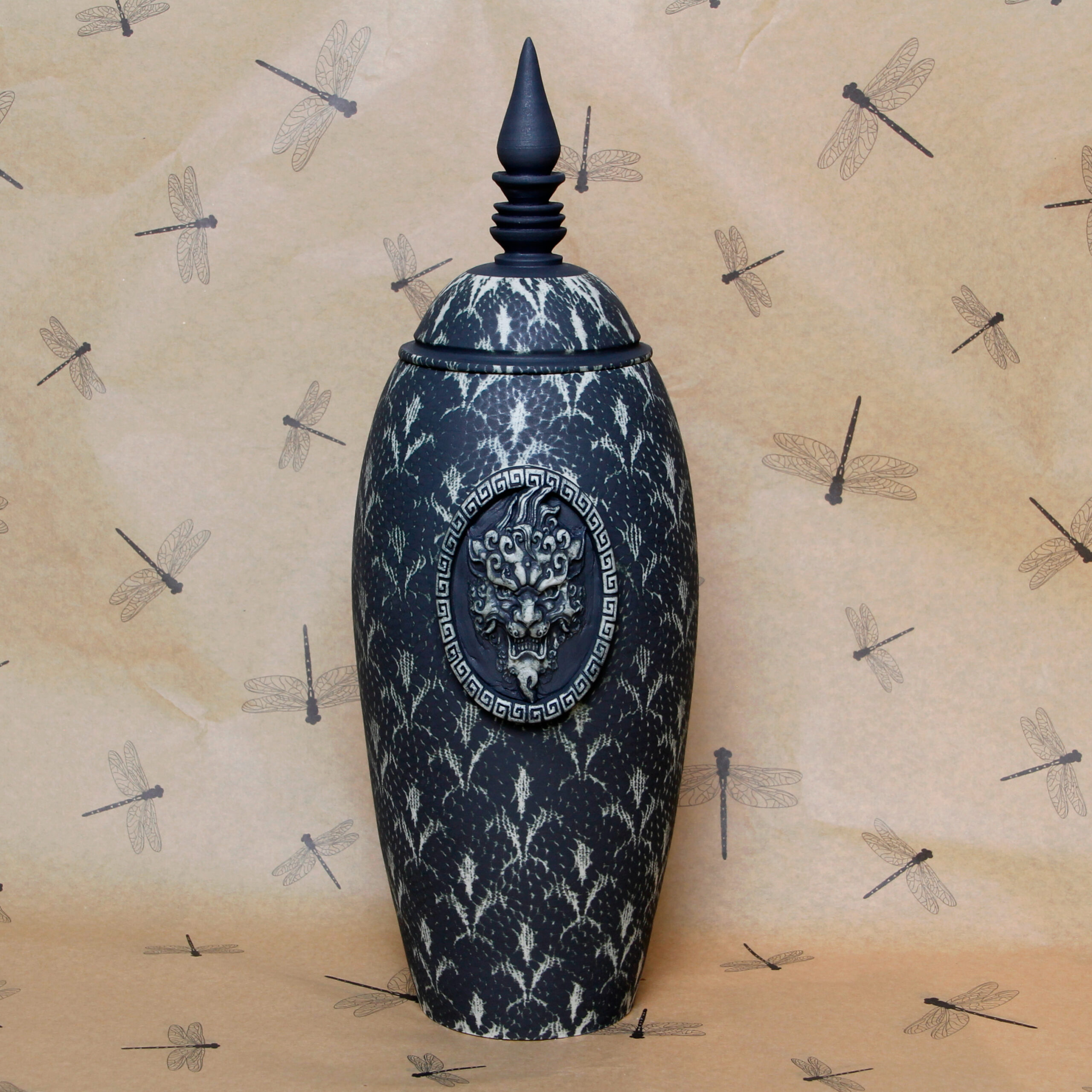 a dark and elegant ceramic pot with a skull on it